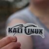A Hand Holding Kali Linux Sticker in Close-up Photography